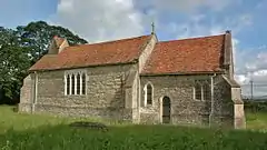 A small church without a tower, with nave and chancel roofed in red tiles