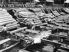 Workers load bundles of lumber for the trip down the flume.