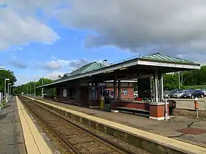 A suburban railway station with two side platforms and a brick station building
