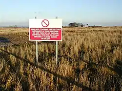 A sign in an upland field warning of dangerous items, toxic material and explosives