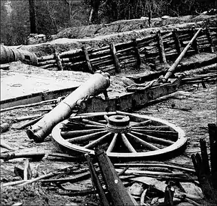 Black and white photo shows a damaged cannon barrel.
