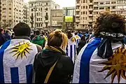 Fans of the national football team on the esplanade of the building watching a game on a big screen