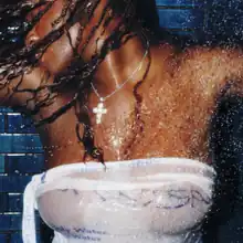 A woman wearing a white dress being sprayed by shower water