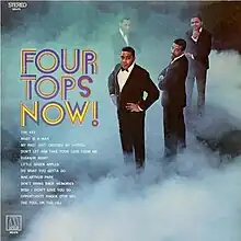The band posing in suits, standing among mist