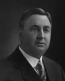 old photo of a dignified man with wire rim glasses