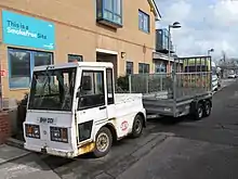 Small, white utility vehicle with a trailer attached