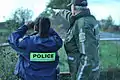 An SQ agent with a pre-2016 uniform observing the border with a RCMP agent