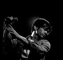 A black-and-white photograph of a man holding up a microphone.