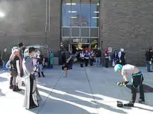 People in costumes watching someone breakdancing in front of a building