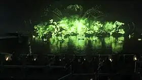 Screenshot from the episode, featuring the green "wildfire" explosion at night over a body of water