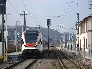 Red-and-white trains on double-track railway line with side platforms