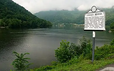scenic river view with mountains covered with trees and historical marker