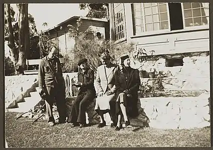 Gavin Arthur, standing, and Janet Flanner, Esther Murphy, and Solita Solano sitting on a rock wall, between 1945 and 1955