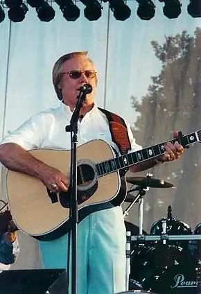 Country music singer George Jones singing while holding a guitar.