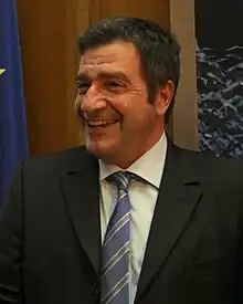 Photographie d'un homme souriant avec en arrière-plan le drapeau européen.