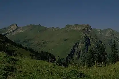 The Giebel (above the left of the three firs, far right) from the Roßkopf. The prominent pinnacle to the left on the arête is the Berggächtle. On the far left is the Schneck.