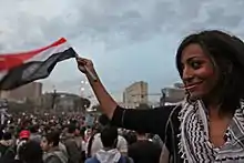 Ibrahim waving a small Egyptian flag in a crowd at a February 2011 protest