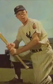 A man in a white baseball uniform and navy blue cap