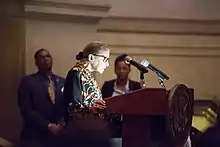 Ginsburg speaking at a podium