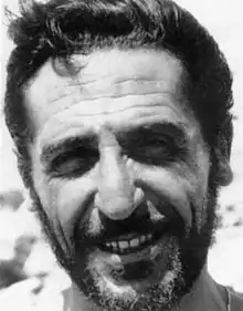 Black and white image of Giuseppe Fava grinning into the camera while squinting