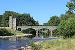 a river crossed by a bridge on the left of which is a tower