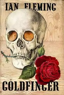 Cover showing a rose held in the teeth of a skull with gold coins for eyes. At the top is the name "IAN FLEMING"; at the bottom is "GOLDFINGER".