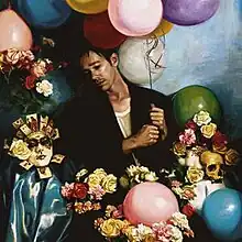 A man surrounded by a skull, mask, and roses while holding a bunch of different colored balloons.