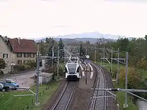 White train at island platform between double-track railway line