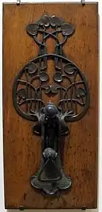 Art Nouveau-style metal door knocker on a wooden door