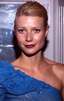 A blonde-haired young woman in a blue off-the-shoulder dress