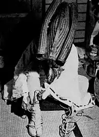 A pilgrim performing kaihōgyō laces waraji over tabi, 1954