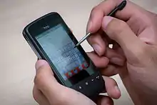 A smartphone being operated with a stylus.