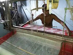 This weaver is weaving a piece of cloth about as wide as he can span. Hooghly district, West Bengal.