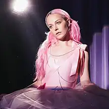 A photo of a woman with pink hair in a pink tutu onstage