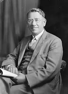 Harry Tombs sitting in a suit and jacket in a black-and-white photograph