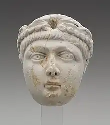 A Miniature portrait head of a a young boy with a full face and short, straight hair. He wears a pearl-edged diadem, which identifies this head as portrait of an Emperor. The head greatly resembles depictions of the Theodosian princes. This marks the identification of the head to be either Honorius, Arcadius, or Valentinian II.