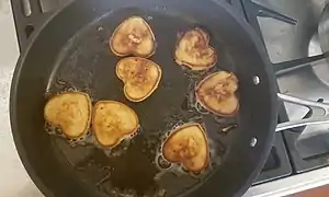 Pancakes made in the shape of a heart on a frying pan