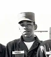 A black and white photograph of five men wearing Army uniforms and standing together as a group