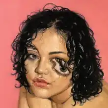 The head of an olive-skinned woman with short curly hair is shown, amidst a pink background. Her eyes are partially distorted, with visual effects used to create a second pair of eyes and a crack directly underneath her right eye, following down to her lips.