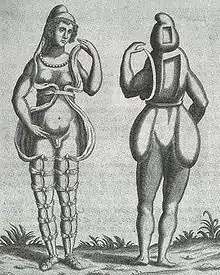 A front and back illustration of a Renaissance-era hermaphrodite showing a person with female facial features, breasts, and what appears to be a small penis or large clitoris. She wears a small hood and open robe tied multiple times around the legs. Where it opens in the front, the apparent rear appearance shows it to be perhaps a shell of some kind, as one with her body. Two squares are missing from her the back of her head and torso. She has no buttocks.