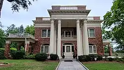Two story brick home with white columned front porch.