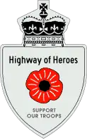 A Highway of Heroes reassurance marker with a red poppy flower in place of a number. Above that is the text Highway of Heroes, and below it SUPPORT OUR TROOPS.