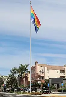 A rainbow flag on a tall flagpole