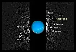 Composite of multiple Hubble images of the Neptune system, with the moons appearing as bright white dots. The fainter dot to the upper right is Hippocamp, circled and labeled to distinguish it from other moons in this image.