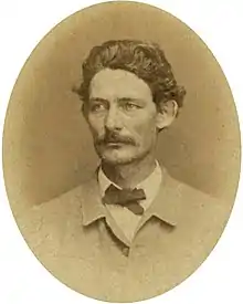 Sepia toned and oval photo shows Hiram B. Granbury with a moustache and thick hair wearing a white shirt and light colored coat.