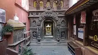 Entrance gate to the Golden Temple in Patan, with a jahru on the left
