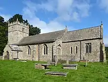 A stone church seen from the south with a battlemented tower on the left