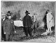 Black and white photo of firemen carrying a stretcher with a body covered in a white sheet
