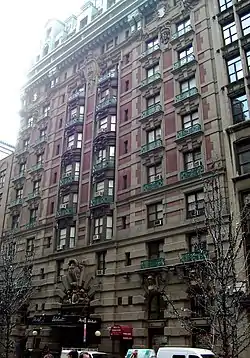View of the Hotel Wolcott as seen from across 31st Street. The facade is largely made of red brick and stone, except at the base, where it is made entirely of stone. The top of the hotel contains windows within a mansard roof.