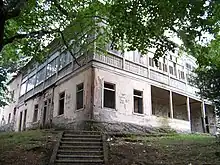 An abandoned two-story mansion missing numerous windows and covered in graffiti